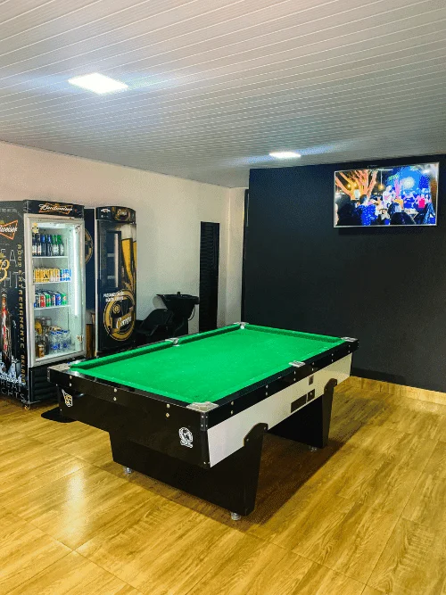 Área de lazer completa na Barbearia Santana com sinuca, TV, geladeira de bebidas e lavatório para clientes em Rio Verde